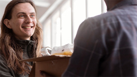 Smiling man receiving package from support worker